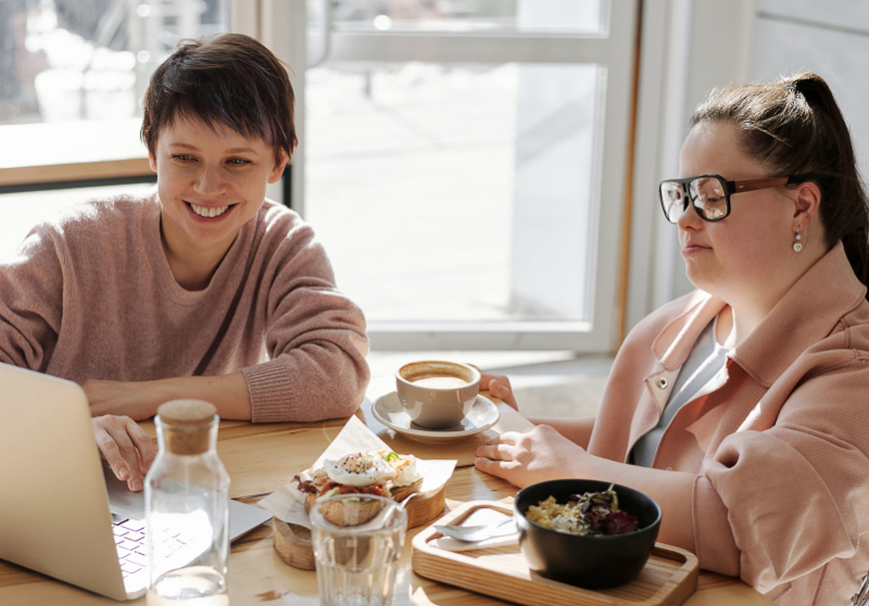 Zwei Personen die Kaffe trinken und dabei essen.